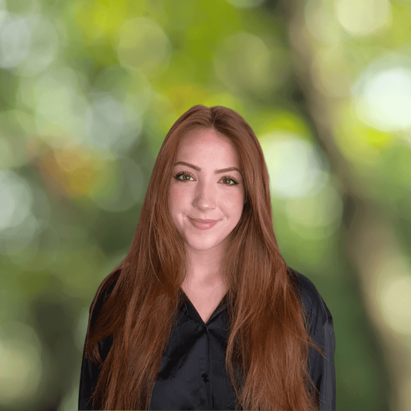 Person with long red hair wearing a black shirt against a blurred green background.