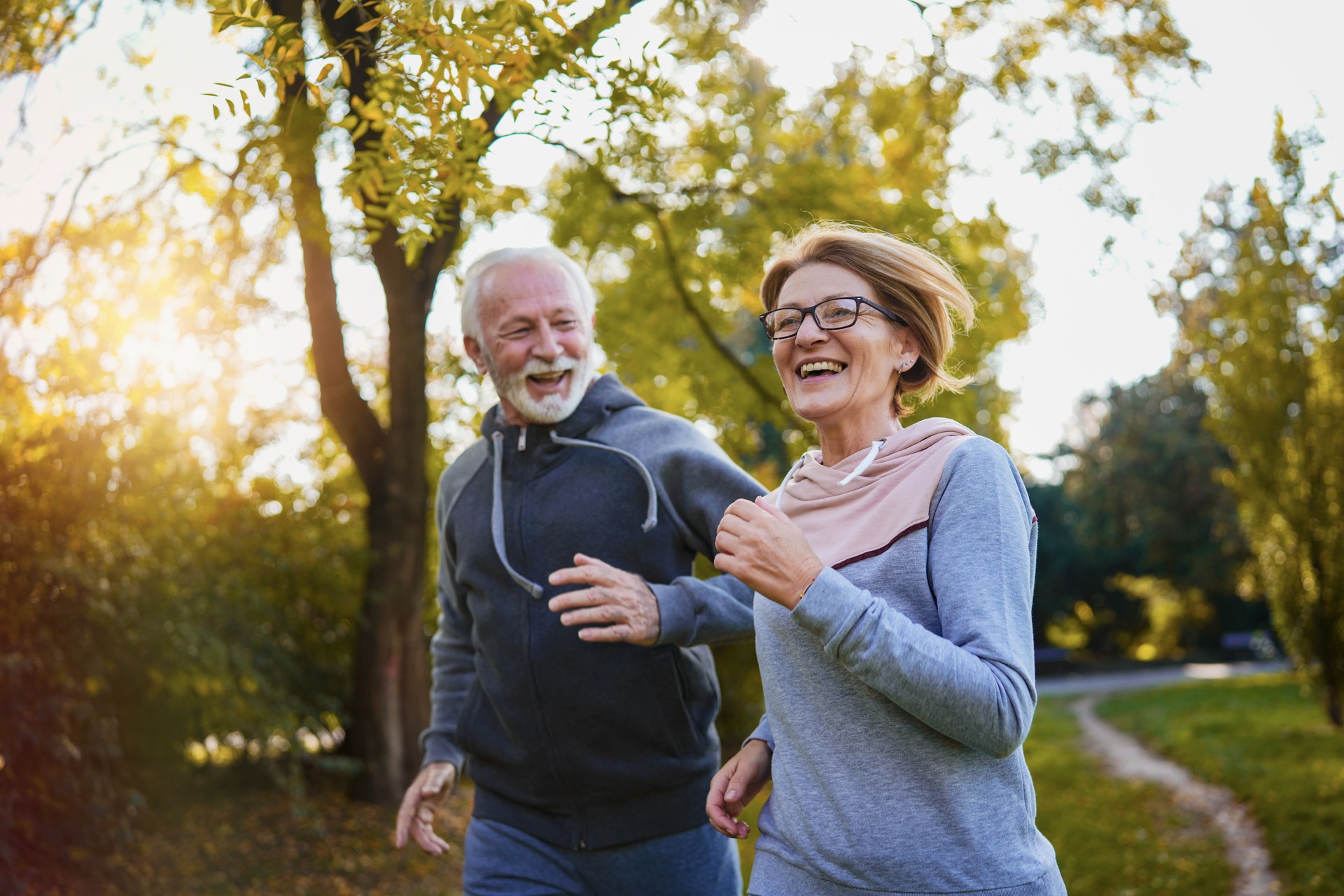 Cheerful active senior couple jogging in the park