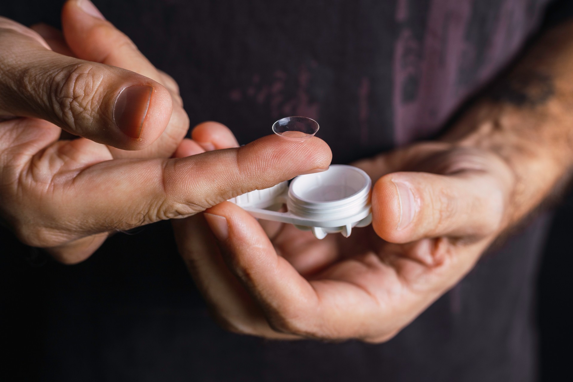 Male hand manipulates a contact lens